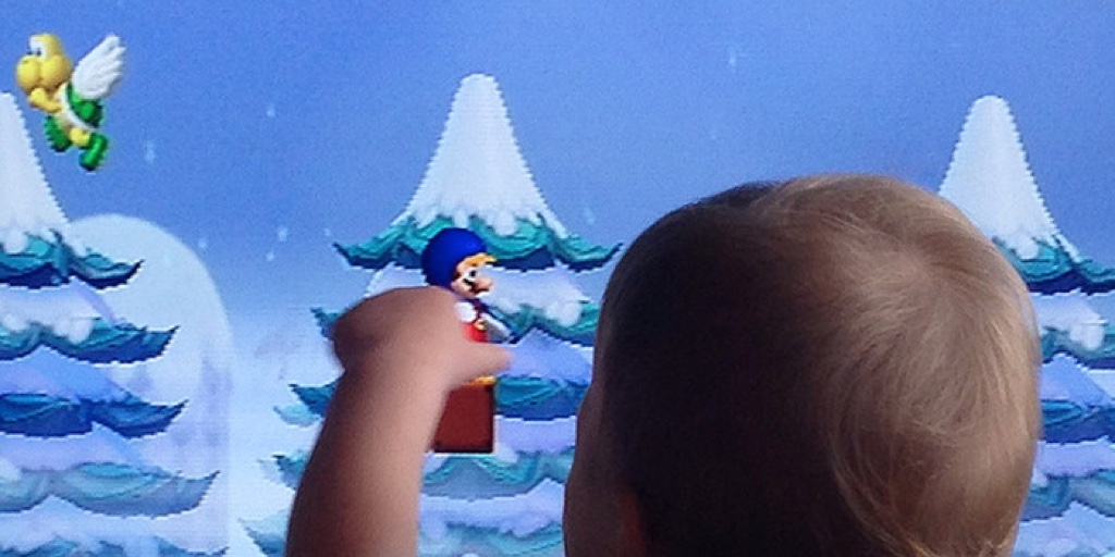 A baby pointing to Super Mario on a screen