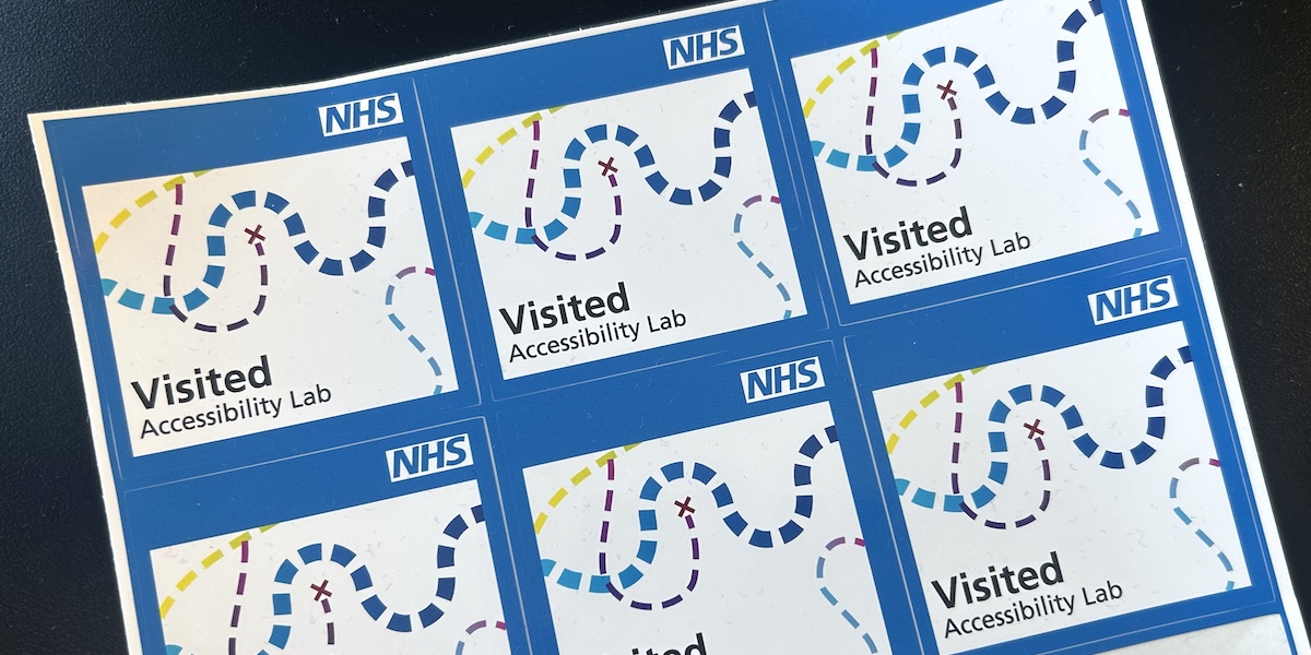 A sheet of NHS stickers that say “visited accessibility lab”. An illustration of wavy dashed lines make it look like a map.