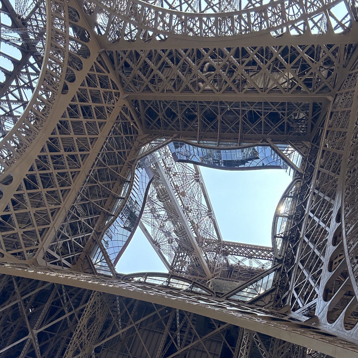 Intricate geometric metal structure with clear blue sky in the distance.