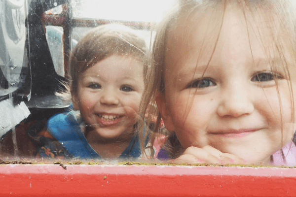 My 2 little girls, smiling in a phone box.