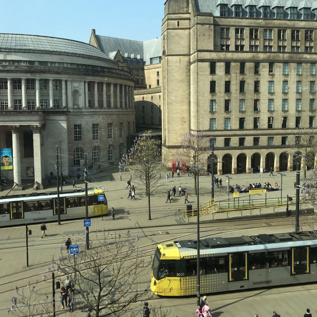 St Peter's Square in Manchester, you can see old buildings, people walking and trams